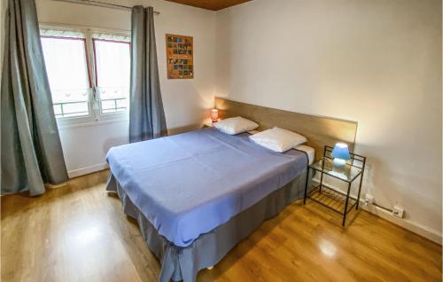 Schlafzimmer mit einem Bett mit blauer Bettwäsche und einem Fenster in der Unterkunft 2 Bedroom Cozy Home In Beaulieu in Beaulieu