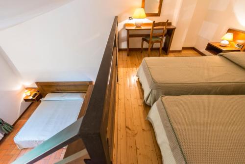 a room with two beds and a table with a desk at Hotel Bellavista in Abetone