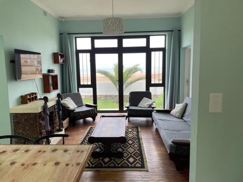 Una sala de estar con un sofá y sillas y una ventana grande. en Seafront house, en Swakopmund