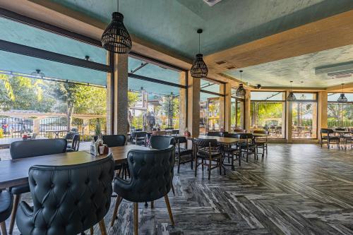 un restaurante con mesas, sillas y ventanas grandes en Lecardo Hotel en Aheloy