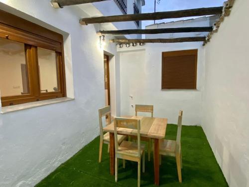 einen Holztisch und Stühle in einem Zimmer mit grünem Gras in der Unterkunft Casa Buitreras in El Colmenar