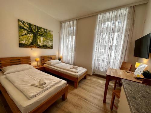 a bedroom with two beds and a desk and a tv at AJO Vienna Messe - contactless check in in Vienna