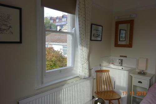 um quarto com uma janela com uma cadeira e um radiador em Westley B&B em Uplyme