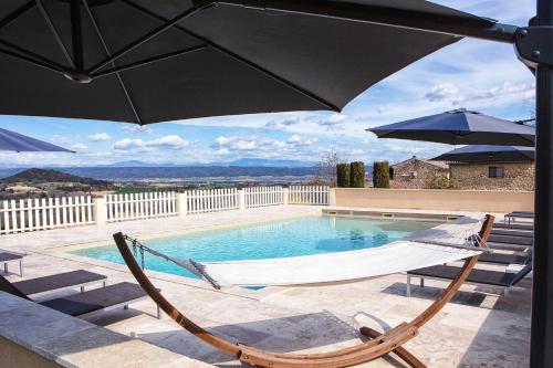 a swimming pool with two chairs and an umbrella at La Magnanerie en Provence in Niozelles