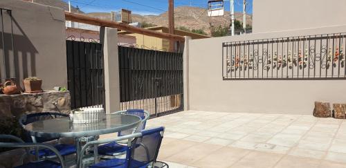 a patio with a glass table and blue chairs at La Casa de los Molles in Tilcara