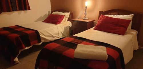 a room with two beds with red pillows at La Casa de los Molles in Tilcara