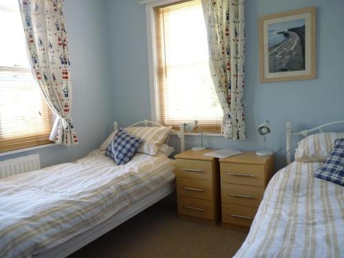a bedroom with two beds and two windows at Westley B&B in Uplyme