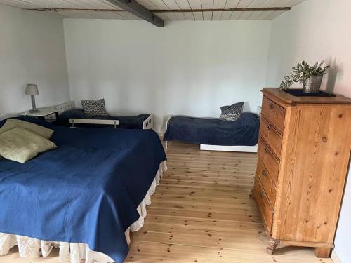 a bedroom with a blue bed and a wooden dresser at Öja in Ystad