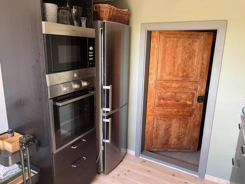 a kitchen with a refrigerator and a wooden door at Öja in Ystad