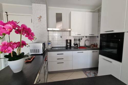 une cuisine avec des placards blancs et un vase avec des fleurs roses dans l'établissement Le Mentonnais - Appartement Carré d'Or Menton, à Menton