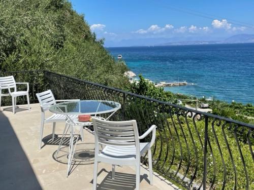 einen Tisch und Stühle auf einem Balkon mit Meerblick in der Unterkunft VILLA MARGARITA in Agios Ioannis Peristerion