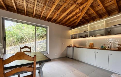 a kitchen with a table and a large window at Villa Magnolia in Rabo de Peixe