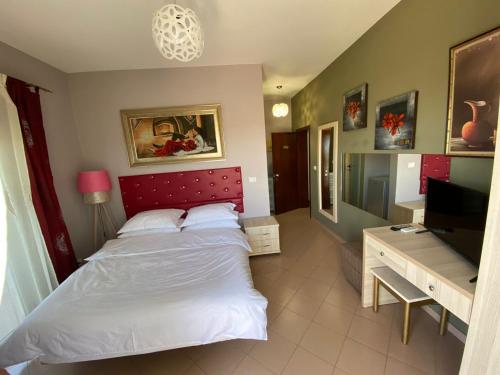 1 dormitorio con 1 cama con cabecero rojo y TV en Prince Hotel Fier, en Fier