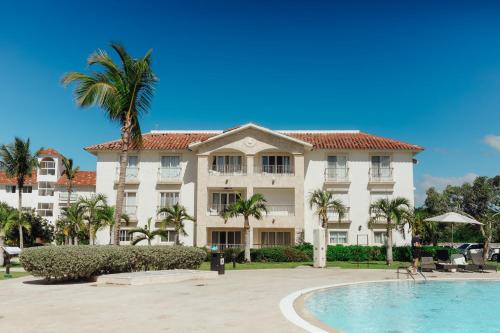 a large white building with a palm tree and a swimming pool at Apartment in Dominicus in Bayahibe