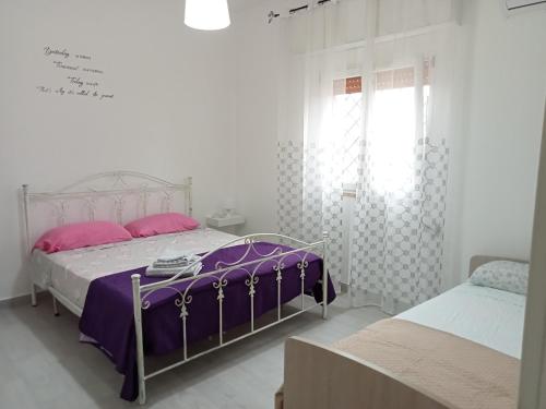 a white bedroom with two beds and a window at Casa Paky in Punta Prosciutto