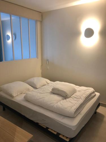 a bed in a room with a light on the wall at NAUZAN in Vaux-sur-Mer