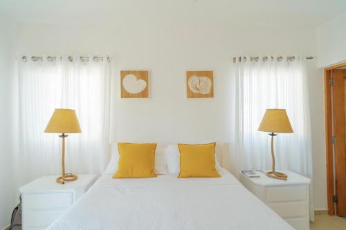 a white bedroom with two lamps and a bed at Apartment in Dominicus in Bayahibe
