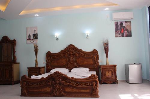 a bedroom with a large wooden bed with white sheets at Hotel Nine Brothers in Batumi