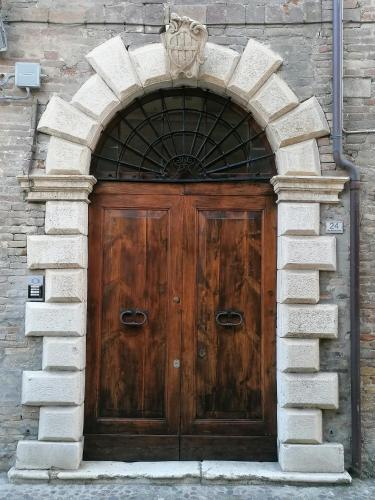 una grande porta in legno in un edificio in pietra di Palazzo Trevisani a Porto San Giorgio