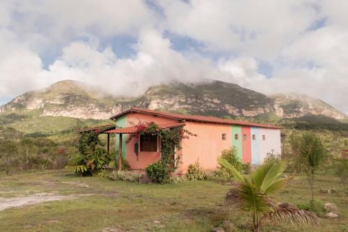 una casa en un campo con una montaña en el fondo en Pousada Serra Aquarela, en Ibicoara