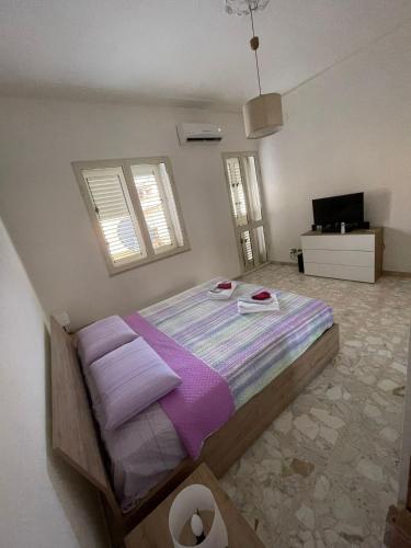 a bedroom with a large bed with purple blankets at Spagna Apartament in Siracusa