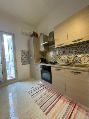 a kitchen with wooden cabinets and a rug on the floor at Spagna Apartament in Siracusa