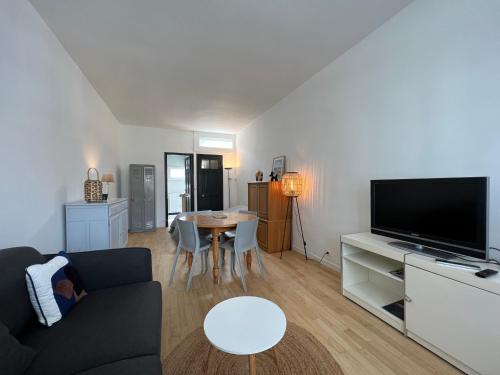 un soggiorno con divano, TV e tavolo di Petite maison de charme a Le Touquet-Paris-Plage