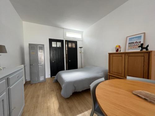 Un dormitorio con una cama y una mesa. en Petite maison de charme, en Le Touquet-Paris-Plage