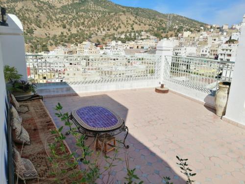 a balcony with a table and a view of a city at Dar Ines in Moulay Idriss Zerhoun