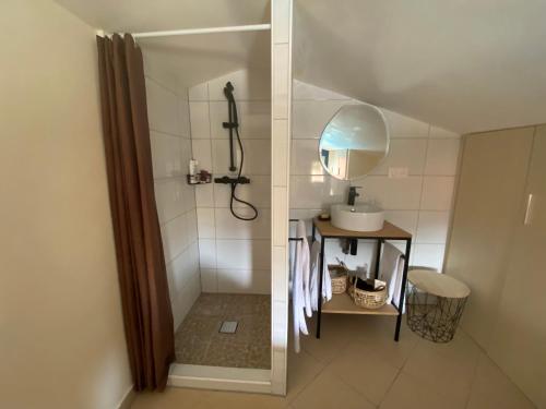 a bathroom with a shower with a sink and a mirror at Lozari Beach in Belgodère