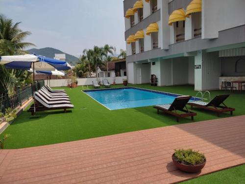 a hotel with a pool and chairs and an umbrella at Hotel Porto Di Mare in Ubatuba