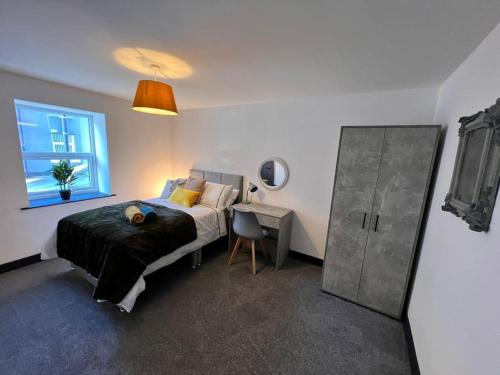 a bedroom with a bed and a desk and a window at Maxwell's Corner, Modern Coastal Apartment in North Shields