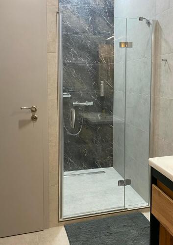 a shower with a glass door in a bathroom at Corner Apartman in Kőszeg