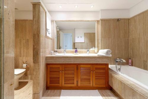 een badkamer met een bad, een wastafel en een spiegel bij Los Monteros Palm Beach - ground floor apartment in Marbella