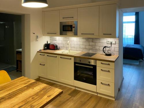 cocina con armarios blancos y suelo de madera en Corner Apartman en Kőszeg