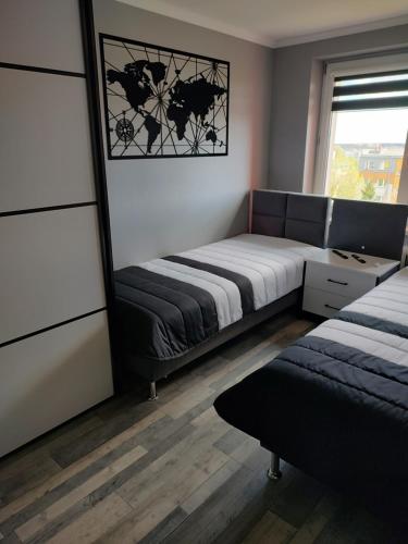 a bedroom with two beds and a window at Apartament MERCURY in Ełk