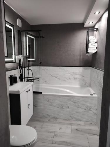 a bathroom with a tub and a sink and a toilet at Apartament MERCURY in Ełk