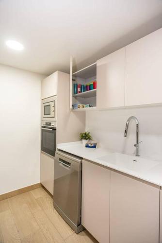 a kitchen with white cabinets and stainless steel appliances at Gran piso en Puerto deportivo Marina Palamós IDEAL FAMILIAS in Palamós