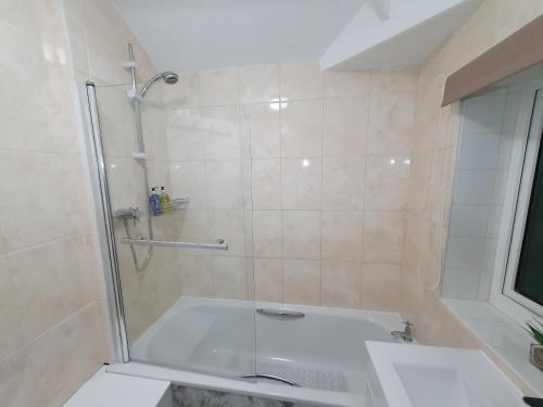 a bathroom with a tub with a glass shower door at Yucca cottage in Kendal