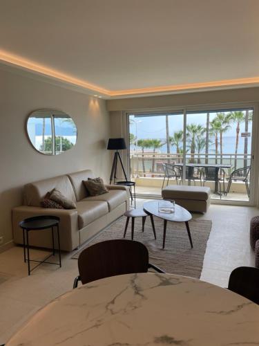 a living room with a couch and a table at Appartement Rottaro luxueux 2 ch 2 sdb face à la mer in Cannes