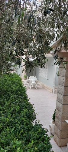 a white bench sitting on a patio under a tree at Villa NIKA & KARLO Makarska in Makarska