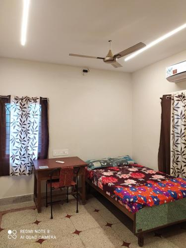 a bedroom with a bed and a table and windows at Anve's Airport Nest in Visakhapatnam