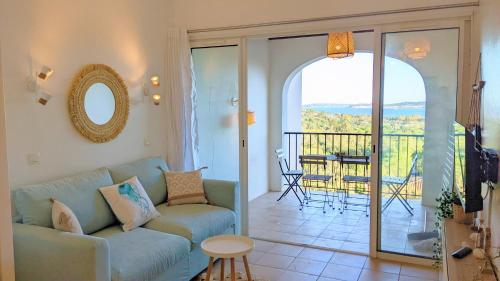 d'un salon avec un canapé et un balcon. dans l'établissement Vue Mer et clim Les Restanques Pivoines 1136, à Grimaud