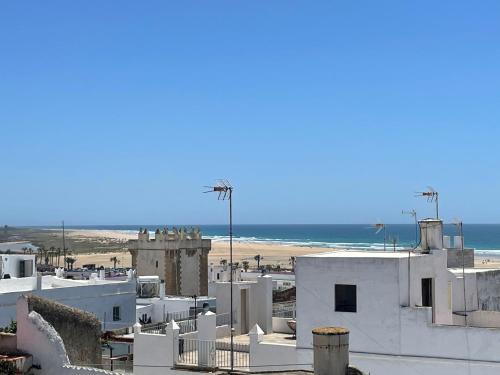 a view of a white building and the beach at Apartamento Conil Playa & Centro, perfecto descanso, con Aire Acond y WIFI in Conil de la Frontera