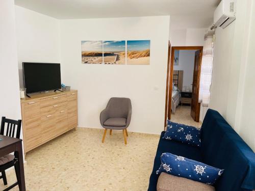 sala de estar con sofá azul y TV en Apartamento Conil Playa & Centro, perfecto descanso, con Aire Acondicionado y WIFI en Conil de la Frontera