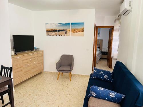 sala de estar con sofá azul y TV en Apartamento Conil Playa & Centro, perfecto descanso, con Aire Acond y WIFI, en Conil de la Frontera