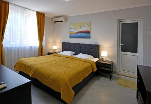 a bedroom with a large bed with a yellow blanket at Villa Holiday in Balchik