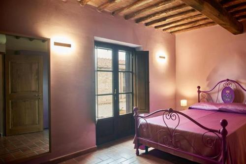 a bedroom with a pink bed and a window at Podere Sant'Antonio in Asciano