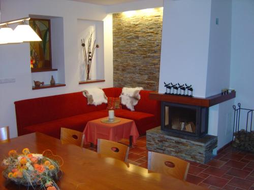 a living room with a red couch and a fireplace at Apartmánový dům Bobrůvka in Bobrŭvka