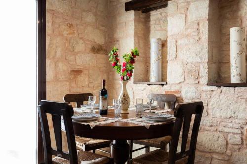 a table with a bottle of wine and a vase with flowers at Villa Õtium in Epáno Váthia